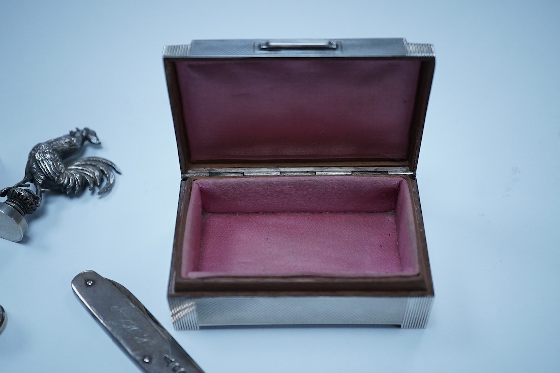 A George VI Art Deco engine turned silver mounted trinket box, by Dudley Russell Howitt, Birmingham, 1947, width 85mm, together with a late Victorian silver fruit knife, a silver thimble, a white metal cockerel mounted s